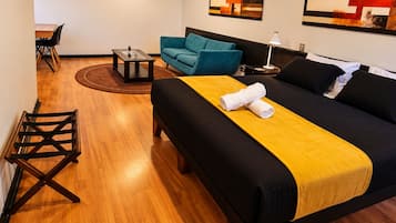 A hotel room with a bed, a sofa, a small table, and a chair.