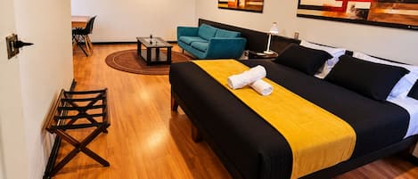 Una habitación de hotel con cama, sofá, una mesita y una silla.