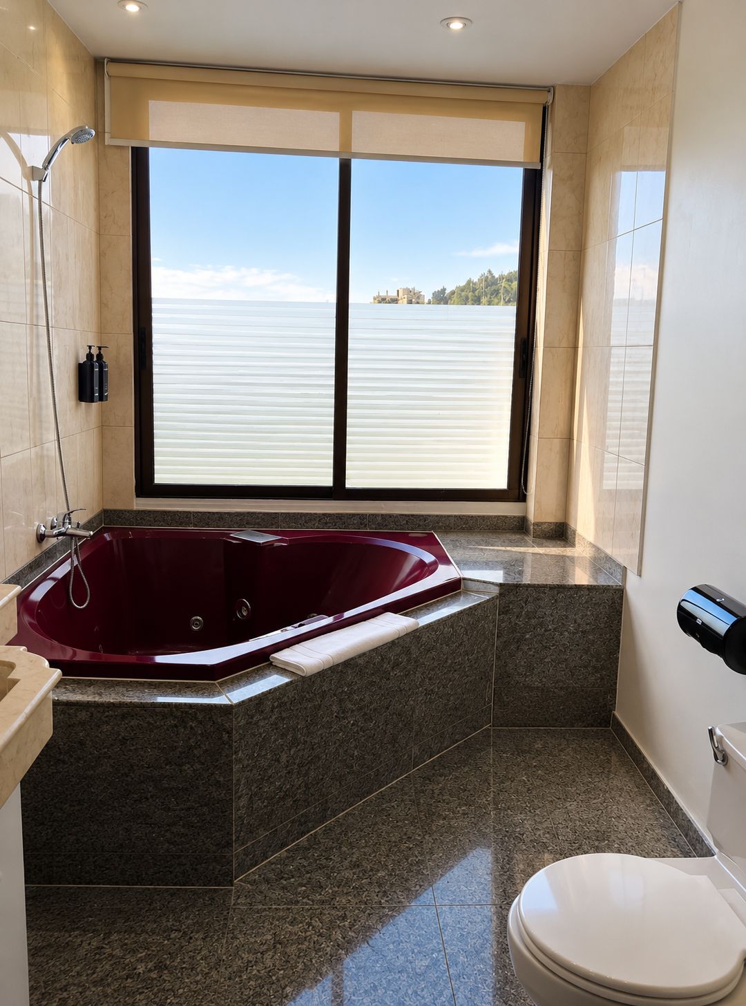 Un baño con una bañera grande, un inodoro y una ventana con vista a un cuerpo de agua.