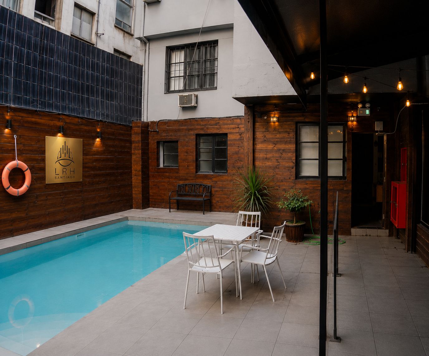 Una piscina con cubierta de madera, una banca y una mesa con sillas.