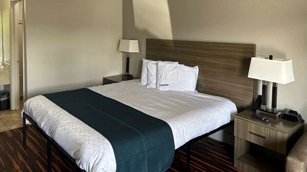 Una camera d'albergo con un letto, due comodini, una lampada e una sedia.