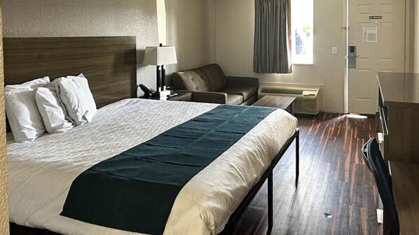 Una camera d'albergo con un letto grande, una scrivania, una sedia e un divano.