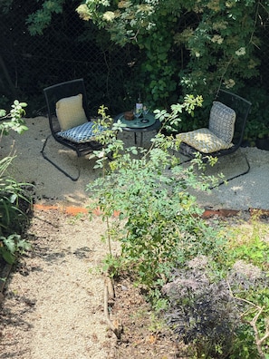 Un espace extérieur aménagé avec deux chaises et une table, entouré de gravier et de verdure.