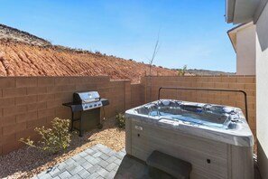 A backyard with a barbecue grill and a hot tub.