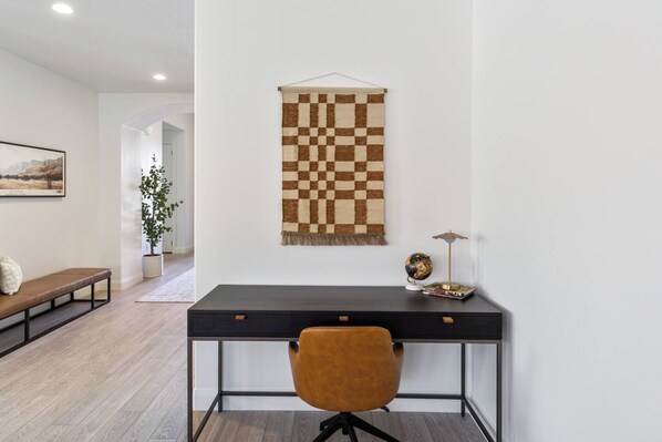 A modern office space with a desk, chair, and a hanging tapestry.