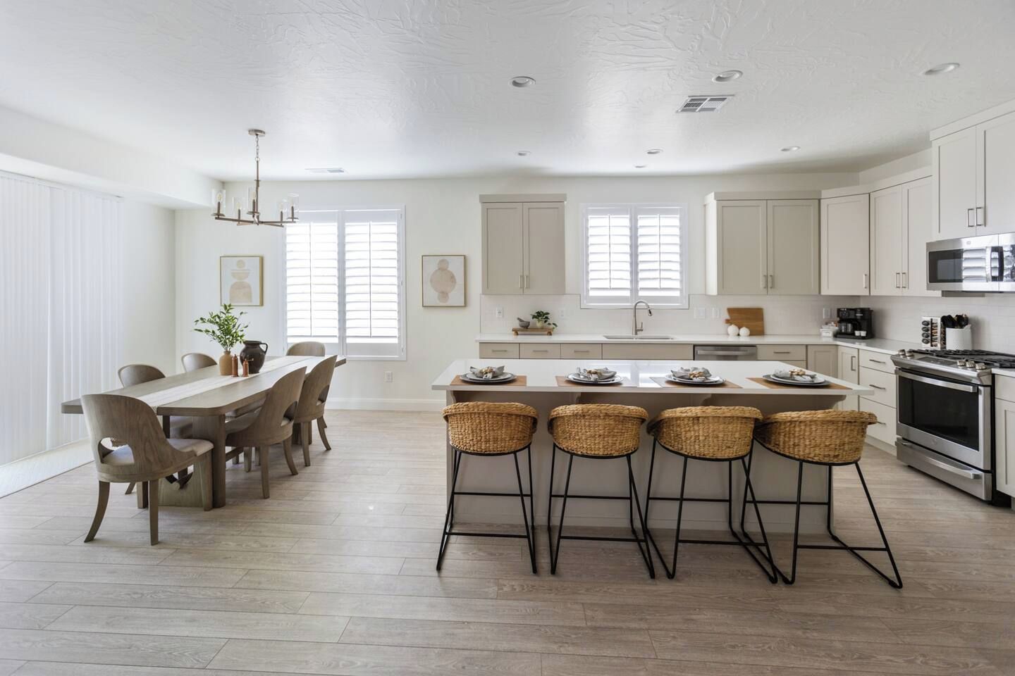 A modern kitchen with a central island, bar stools, and a dining area with a table and chairs.