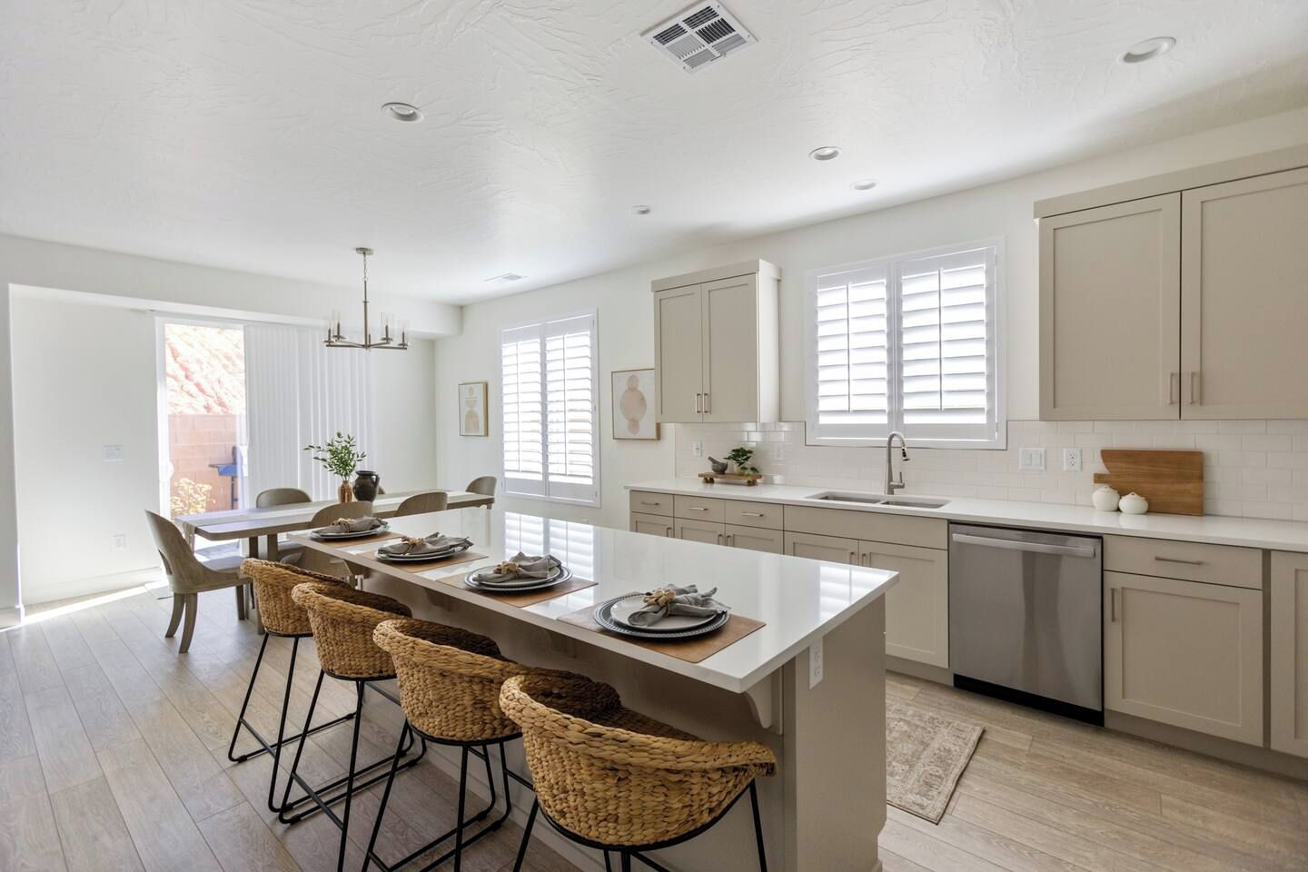 A modern kitchen with a central island, bar stools, and a dining area with a table and chairs.