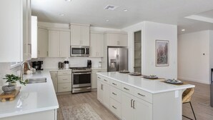 A modern kitchen with white cabinetry, stainless steel appliances, and a central island. - 3 Master Suites with Private Baths, Kings Beds, Private Hot Tub, EV, BBQ (Washington)