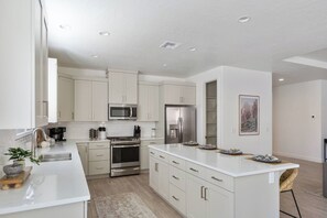 A modern kitchen with white cabinetry, stainless steel appliances, and a central island. - 3 Master Suites with Private Baths, Kings Beds, Private Hot Tub, EV, BBQ (Washington)