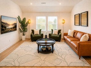 Un salon comprenant un canapé, deux fauteuils, une table basse, une plante en pot et un tableau accroché au mur.
