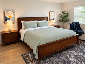 Une chambre à coucher avec un lit en bois, deux tables de chevet, une commode, une lampe sur pied, une plante en pot et une fenêtre avec des stores.