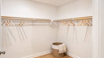 Un dressing ouvert avec des cintres en bois et un panier en osier.