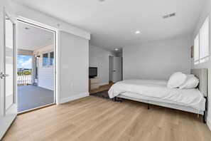 A bedroom with a bed, a television, and a door leading to a balcony. - Luxury Ocean-Block Penthouse, Ocean Views (Seaside Heights)