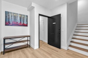 A hallway with a wooden bench, a black door, and a staircase. - Luxury Ocean-Block Penthouse, Ocean Views (Seaside Heights)