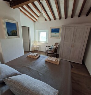 Quarto com cama, cadeira, guarda-roupa e janela.