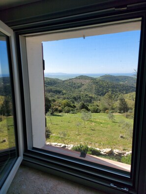 Finestra amb vista a un paisatge verd i a les colines llunyanes.