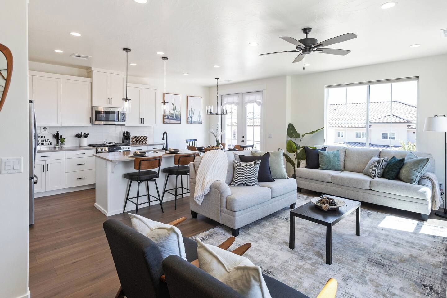 A modern kitchen with white cabinets, a central island, bar stools, and pendant lighting.