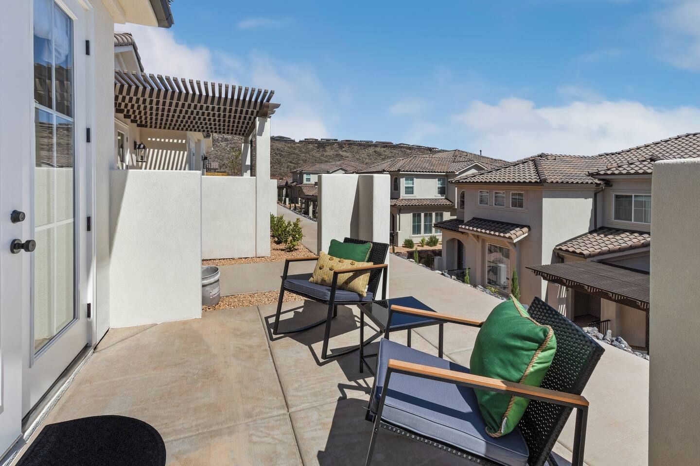 Varanda com móveis de exterior, pérgola e vista para casas vizinhas.