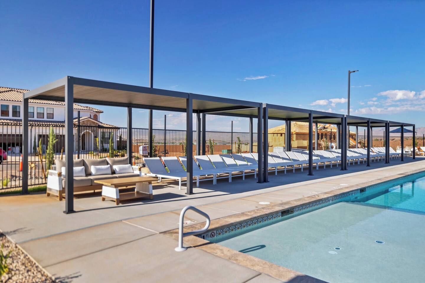 A poolside area with lounge chairs and a covered seating area.