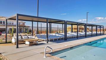 A poolside area with lounge chairs and a covered seating area.