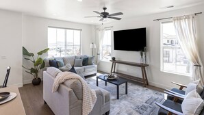 Ein modernes Wohnzimmer mit einer Couch, einem Couchtisch und einem Flachbildfernseher.