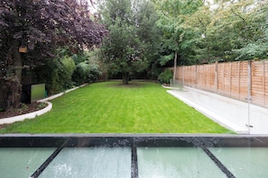 Un jardin avec une pelouse bien entretenue, une clôture en bois et une variété d’arbres.