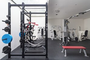 Een sportschool met gewichthefapparatuur, banken en diverse fitnessapparaten.