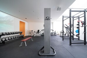 A gym with weightlifting equipment, a bench, and dumbbells. - Large Modern London Townhouse with Cinema, Gym, Garden, Pool table, Large spaces (London)