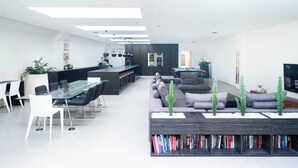 Ein modernes Wohnzimmer mit einem Glastisch, bequemen Sitzgelegenheiten und einer integrierten Bücherwand.