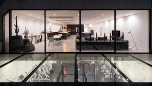 Un interior moderno con un separador de vidrio, un comedor y una sala de estar con piscina.