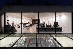Un intérieur moderne avec une cloison en verre, un coin repas et un salon avec piscine.