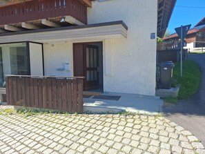 A building with a wooden fence, a door, and a small outdoor area with a bench.
