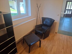Una habitació amb una cadira de pell negra, un otomà negre i un moble prestatge negre.
