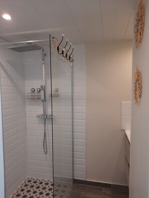 A modern shower with a glass enclosure, a handheld showerhead, and a wall-mounted towel rack. - TOPAZE Studio with Ocean View (Le Diamant)