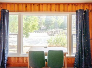 Ein Zimmer mit Holzwandverkleidung, einem fenster mit Vorhängen und einem Tisch mit zwei Stühlen.