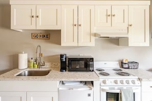 A kitchen with white cabinets, a microwave, a coffee maker, a stove, and a sink. - Deschutes River View + Pioneer Park. Short Walk to Downtown Along River Path (Bend)