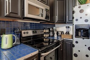 A kitchen with a stove, microwave, coffee maker, and a refrigerator with a water dispenser. - Colorful & Quirky 1-BR Loft w/Private Deck | MICA, JH & UMMC (Baltimore)