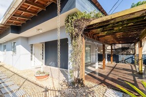 A modern house with a covered patio area, a potted plant, and a chain-link fence.