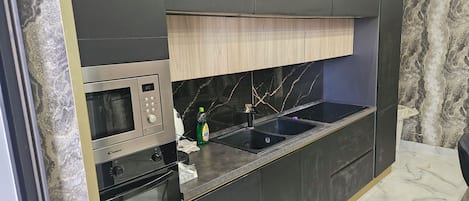 A modern kitchen with a built-in microwave, oven, and sink.