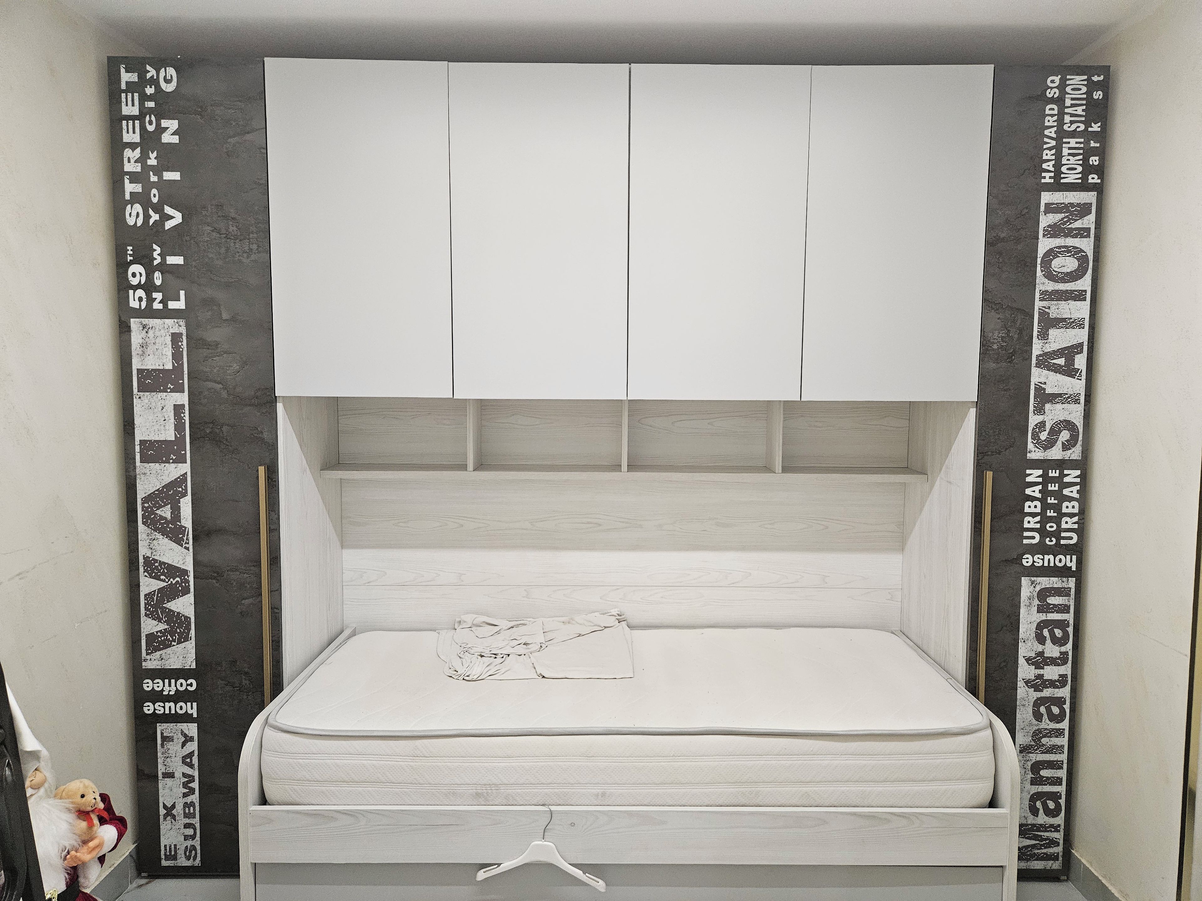 A small, compact bed with a white mattress and a simple headboard.