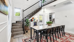 A spacious kitchen with a dining area, a staircase, and a large window. - Northgate: Closest Home to Aggieland! 3BR, 2.5BA (College Station)