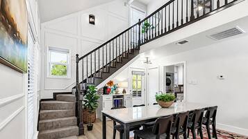 A spacious kitchen with a dining area, a staircase, and a large window.