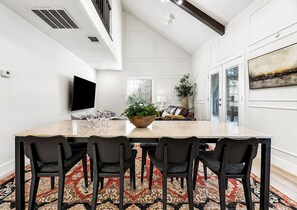A spacious dining area with a large table, six chairs, and a television mounted on the wall. - Northgate: Closest Home to Aggieland! 3BR, 2.5BA (College Station)