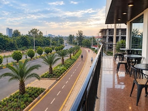 A balcony with outdoor seating overlooking a road lined with palm trees and a cityscape in the distance. - Nile View Hotels  (Bahir Dar)