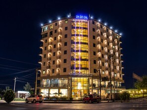 Um hotel com vários andares, um letreiro grande no topo, janelas amplas e varandas.