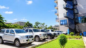 A row of white SUVs parked in front of a modern building with a blue staircase.