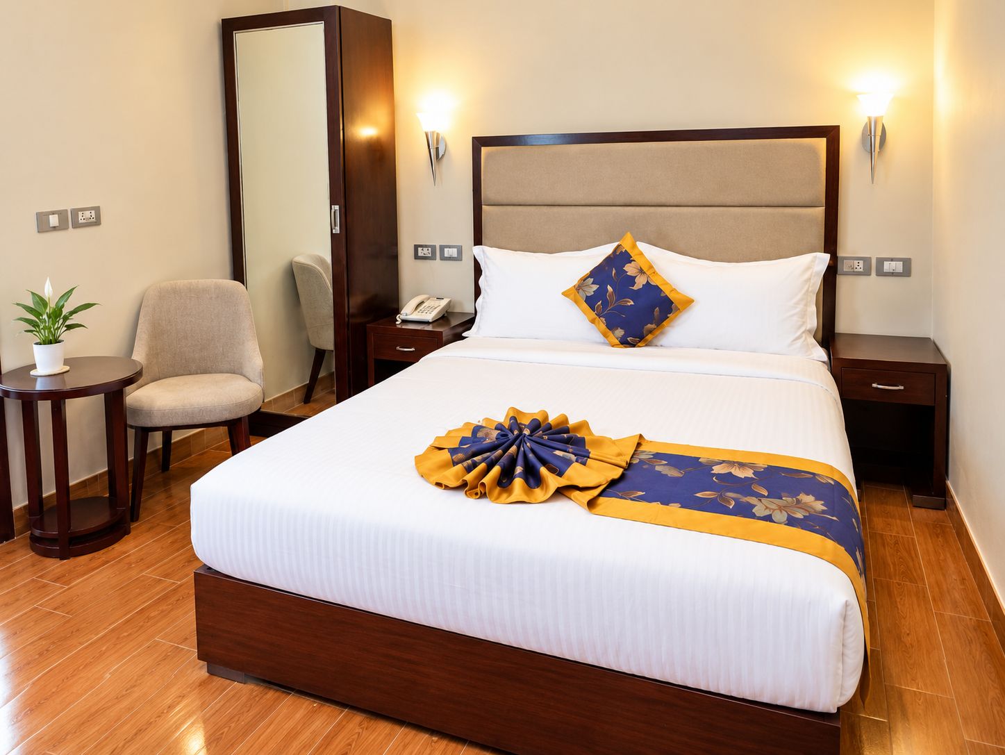 Une chambre d’hôtel avec un grand lit, des tables de chevet, une chaise, un miroir et une plante en pot.
