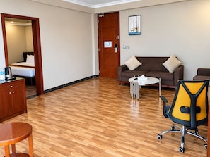 A hotel room with a wooden floor, a sofa, a coffee table, a desk, and a chair. - Nile View Hotels  (Bahir Dar)