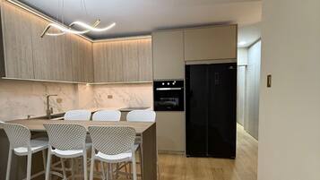 A modern kitchen with a bar area, wooden cabinets, and a black refrigerator.