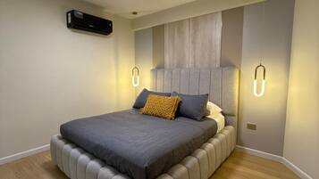 A modern bedroom with a large bed, built-in headboard, and wall-mounted lighting.